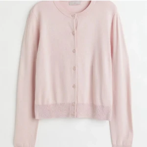 Ljusrosa kofta från H&M - Supersöt ljusrosa kofta från H&M med rund halsringning och knappar hela vägen framtill. Långärmad och i mjuk, tunnstickad bomullsblandning som är perfekt för lager-på-lager. Enkel och stilren design som passar till allt.