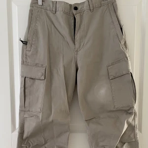 Beige cargopants från H&M Regular Fit - Säljer ett par beige cargopants från H&M i regular fit. Byxorna har flera stora fickor på sidorna, elastisk midja bak och klassisk cargostil. Tillverkade i bomull och perfekta för en avslappnad streetlook.