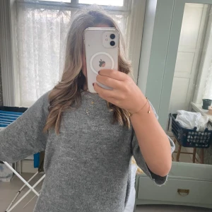 Grå stickad tröja från 157 XS - Mysig grå stickad tröja från 157 i storlek XS. Tröjan har en enkel och stilren design med rund halsringning och kortare ärmar. Perfekt för lager-på-lager och chill dagar. Superenkel att matcha med jeans eller kjol.