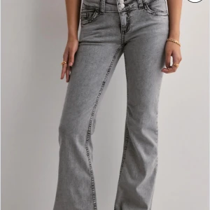 Grå bootcut jeans med broderade fickor - Snygga grå jeans med bootcut-snitt och hög midja. Jeansen har coola broderade detaljer på bakfickorna och klassisk femficksdesign. Perfekta för dig som gillar en avslappnad men trendig look.