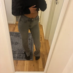 Grå bootcut jeans med hög midja - Säljer ett par gråa jeans med bootcut-modell och hög midja. Jeansen har klassisk femficksdesign och är tillverkade i mjukt denimtyg. Snygg passform som sitter tajt upptill och släpper ut vid bensluten. Perfekta för dig som gillar en stilren och trendig look.