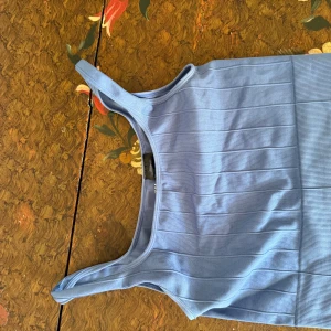 Blå ribbad linnetopp från H&M Sport - Säljer en ljusblå ribbad linnetopp från H&M Sport. Toppen är ärmlös med breda axelband och har en sportig, croppad passform. Perfekt för träning eller en chill vardagslook. Materialet är stretchigt och bekvämt.