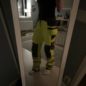 Helly Hansen gula arbetsbyxor - Säljer ett par sjukt snygga arbetsbyxor från Helly Hansen i neon-gult med svarta detaljer och reflexband. Byxorna har flera praktiska fickor, förstärkta knän och är perfekta för dig som vill sticka ut fint på jobbet. Materialet är slitstarkt och passar för tuffa tag. De är helt oanvända med prislappen kvar! Hör av dig om du är intresserad eller har några frågor!🤗 Innerbenslängd: 76cm, Hela benets längd: 104cm.