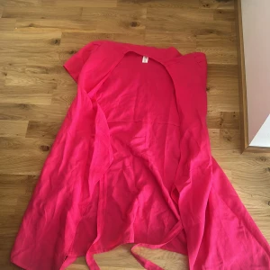 Knallrosa omlottklänning från C-M - Säljer en snygg knallrosa omlottklänning från C-M i storlek 36. Klänningen har korta ärmar och långa band för att knyta i midjan. Materialet är mjukt och lätt, perfekt för varma dagar. Färgen är riktigt poppig och ger en cool vibe till din outfit.