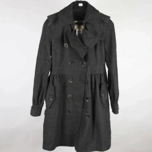 Elegant Thomas Burberry ullkappa i lyxig kashmir & ullblandning - Exklusiv och tidlös klassiker, stl 36, Fint skick  - Elegant kappa från Thomas Burberry i mörkgrå ullblandning (70 % ull, 20 % polyamid, 10 % kashmir). Dubbelknäppt modell med markerad midja, dekorativa ärmknappar och fickor framtill. Varm, mjuk och bekväm – perfekt för vår, höst och vinter. Som jämförelse kostar Burberrys nya ull- och kashmirkappor 30 000–40 000 kr (≈ 2 600–3 500 €) nya. Detta är en investering – en tidlös klassiker som håller hela livet. Jag prutar inte men erbjuder bundlerabatt. Rensar garderoben, kolla mina andra annonser!