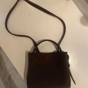 Mörkbrun mocka axelväska mini - Snygg liten axelväska från arket i mörkbrun mocka. 