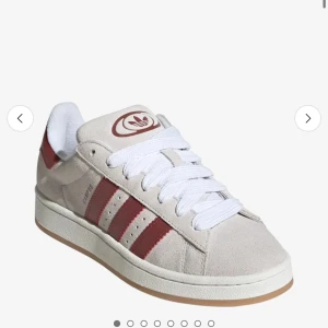 Adidas Campus sneakers beige/röd mocka - Snygga Adidas Campus sneakers i beige mocka med klassiska röda ränder och vit sula. Skorna har vit snörning, rund tå och diskret Adidas-logga på plösen och hälen. Perfekta för dig som gillar retrostil och vill sticka ut med en clean look. Köpte för 1999kr 