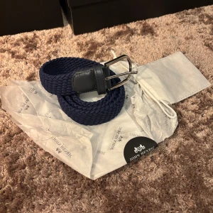 John Henric bälte  - Säljer ett marinblått John Henric bälte i ny sick aldrig använt och dustbag medföljer, ny pris 600kr säljer för endast 299