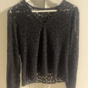 Svart spetsblus XS från vero moda💕 - Svart långärmad blus i genombruten spets från vero moda. Blusen har v-ringning och ett blommigt spetsmönster som ger en snygg och feminin look. Perfekt att styla med jeans eller kjol för en trendig outfit. Bara använd någon enstaka gång🫰😽