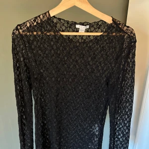 Svart spetsblus från New Yorker - Säljer en svart långärmad blus från New Yorker i genombruten spets. Toppen har rund halsringning och är figurnära med ett elegant spetsmönster över hela plagget. Perfekt för dig som vill ha en stilren och trendig look. Storlek som står på plagget är L men är super liten i storleken så skulle säga att den är typ S-M i storleken