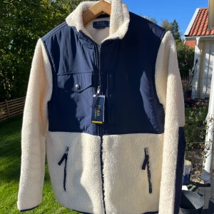 Fleecejacka Polo Ralph Lauren - Schysst från Polo Ralph Lauren fleecejacka i marinblått o krämvit. Storlek S men passar M. Köpt i USA förra vintern så knappt använd. Skriv vid frågor, pris ej hugget i sten 🪨 