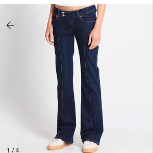 Mörkblå bootcut jeans från 157, S, length short - Mörkblå jeans från 157 i bootcut-modell med låg midja. Klassisk femficksdesign, kontrastsömmar och raka ben som släpper ut nedtill. Jeansen är tillverkade i denim och har dubbla knappar i midjan för extra detalj. Liten slitning mellan benen men inget man tänker på. Original pris 400kr