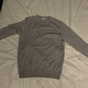 Grå tröja från John Henric - En stilren grå tröja från John Henric i storlek M. Tröjan har rund halsringning, långa ärmar och ribbade muddar vid ärmslut och nederkant det är 100 procent merinoull . Perfekt för dig som gillar en clean och klassisk look. Köpt förra året för 999kr använt max 3 gånger då den är för liten säljer för 450kr kan gå ner i pris vid snabb affär 