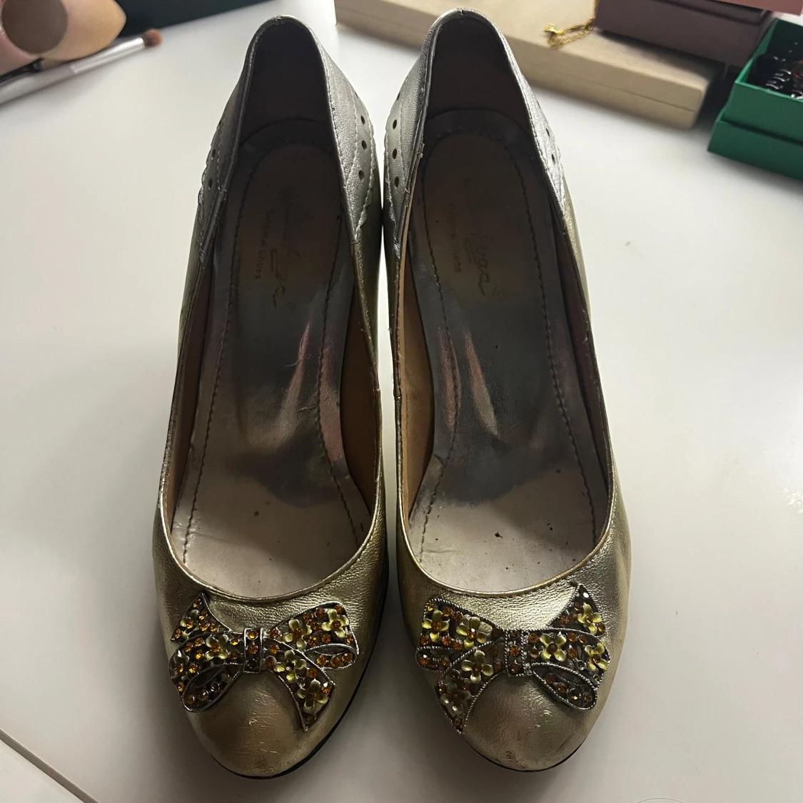 Guldiga pumps med rosett och strass