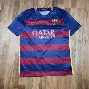 FC Barcelona Neymar Jr 11 15/16 - Säljer en FC Barcelona matchtröja säsong 15/16 från Nike med Neymar Jr och nummer 11 på ryggen. Tröjan har breda blå och vinröda ränder, gula detaljer och klubbmärke på bröstet. Tillverkad i Dri-FIT material för bästa komfort. Snygg krage med röd-gula ränder och texten 'mes que un club' insydd.