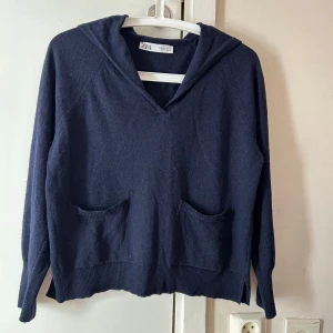 Mörkblå stickad  från Zara - Mysig mörkblå stickad hoodie från Zara med två framfickor och ribbade muddar. Tröjan har en avslappnad passform, lång ärm oPerfekt för kyliga dagar när du vill vara både bekväm och snygg.