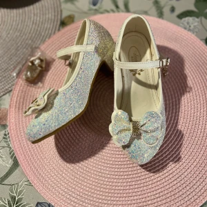 Glittriga pumps med rosett från Aranies  - Superfina pumps i vitt med glittrigt material och en stor dekorativ rosett framtill. Skorna har en låg klack, rund tå och justerbart spänne över foten. Perfekta för dig som vill sticka ut med extra bling och söt detalj på fötterna. Använda en gång på bröllop.