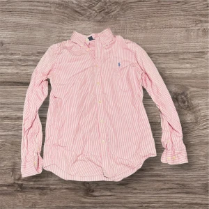 Rosa och vit randig skjorta Ralph Lauren - Säljer en klassisk skjorta från Ralph Lauren i rosa och vitt med smala ränder. Nypris 1099kr