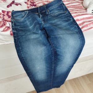 G-Star RAW 3301 Slim jeans blå - Snygga blå jeans från G-Star RAW, modell 3301 Slim. Jeansen har klassisk femficksdesign, orangea sömmar och en tvättad look med ljusare partier framtill. Perfekta för dig som gillar en smalare passform och stilren denim.storlek 27-32