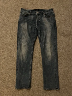 Neuw mörkblå jeans straight fit - Säljer ett par Neuw jenas i mörkblå tvätt med snyggt slitna detaljer. Klassisk femficksmodell med raka ben och normal passform. Tillverkade i mjuk bomullsdenim som sitter skönt hela dagen.