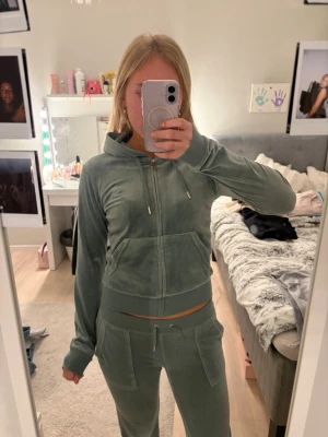 Grön velour loungewear-set - Mysigt juciy-set i mjuk grön velour med zip-hoodie och matchande byxor med dragsko och fickor. Perfekt för chill hemma eller när du vill vara bekväm men ändå snygg. Snygga detaljer med bred mudd och klassisk passform. Tröjan är i storlek S och byxorna är i XS. Det går att köpa settet separat, alltså bara tröjan eller bara byxorna! Priset kan då diskuteras 💞