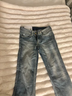 Ljusblå bootcut jeans från weekday - Säljer ett par ljusblå weekday jeans med klassisk bootcut passform. Jeansen har fem fickor, gylf med dragkedja och knapp samt snygga slitningar framtill för en cool look. Perfekta till sneakers eller boots.stl 32