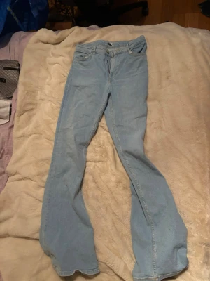 Ljusblå bootcut jeans Zara - Säljer ett par ljusblå bootcut jeans med klassisk femficksdesign och knappgylf. Jeansen har en utsvängd passform nedtill och är tillverkade i mjukt denimtyg. Perfekta för dig som gillar retrovibbar och vill ha ett par bekväma jeans med snygg siluett.