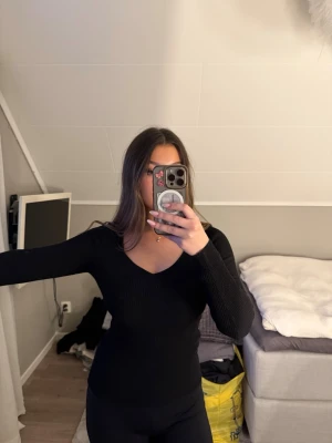 Svart ribbad tröja från H&M - Svart långärmad tröja från H&M med ribbad struktur och v-ringad hals. Snygg och enkel modell som passar perfekt till jeans.