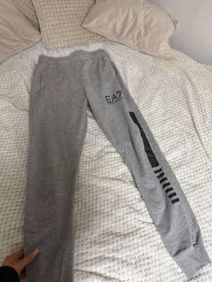 Grå EA7 mjukisbyxor med tryck - Snygga grå mjukisbyxor från EA7 Emporio Armani med svart tryck på ena benet och logga vid fickan. Storlek M skulle säga mer som XS/S.
