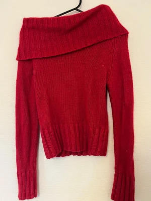 Röd off shoulder stickad tröja - Röd stickad tröja, har en cowl neck som jag alltid haft som off-shoulder. Gjord i 55% Ramie, 20% Angoraull och 25% Nylon.
