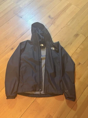 Svart vindjacka The North Face XS - Säljer en svart vindjacka från The North Face i storlek XS. Jackan har huva, meshfoder och dragkedja framtill. Tillverkad i slitstark polyester med DryVent-teknologi som står emot regn och vind. Perfekt för dig som vill ha en clean och funktionell jacka. Den är stor i storleken så passar S också 