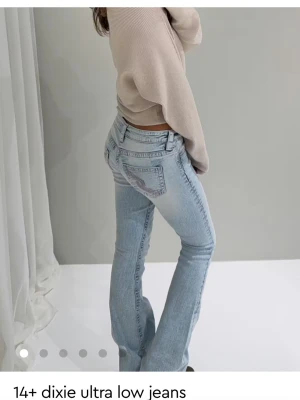 Ljusblå ultra low bootcut jeans - Säljer ett par ljusblå ultra low waist jeans med bootcut passform. Jeansen har klassiska fem fickor, broderad detalj på bakfickan och är tillverkade i mjukt denimtyg. Helt nya med prislapp 