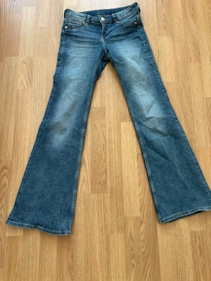 Blå bootcut jeans med låg midja - INTRESSEKOLL Säljer ett par klassiska blå jeans med bootcut och låg midja. Jeansen har fem fickor, bälteshällor och snygg slitning framtill. Om någon är intresserad hör gärna av er kan tänka mig att gå ner i pris!