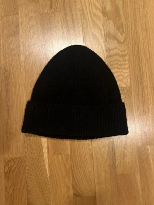 Svart stickad mössa - Skön mössa, passar till allt egentlgien. Köpte den i paket med en likandan vit och har aldirg använt denna svarta, utan bara min vita. Så helt nyskick!