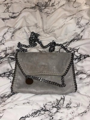 Axelremsväska - Säljer väldigt fin väska med kedjor, den har 2 små innerfickor och 1 lite större innerficka med dragkedja, Kedjorna på väskan är ej justerbara. 