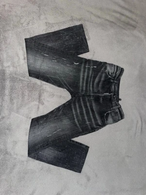 Svarta wide jeans från DSquared2 - Säljer ett par svarta jeans från dsquared2 med breda ben och slitna detaljer. Jeansen har klassisk femficksdesign, normal midja och raka sömmar. Materialet är robust denim i bomull och passformen är loose för en avslappnad vibe.