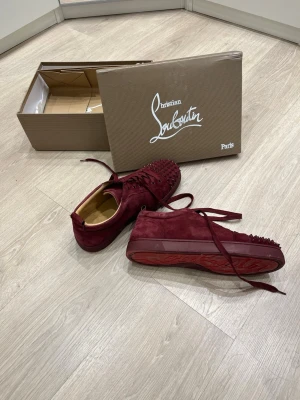 Christian Louboutin vinröd - Ett par mörk röda Christian Louboutin skor storlek 44 men jag har storlek 42 och passar utmärkt! Finns lite slitningar under, inget som syns, inte så använda, kan vara något smutsiga men försvinner enkelt med rengöring om jag ej hinner rengöra dom innan, inga permanenta smuts fläckar, se bilder