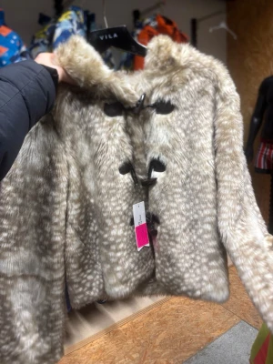 Beige pälsjacka med knappar - Finns alla storlekar. Säljer från min mammas lilla butik då hon inte säljer så bra i butik.                 Pris kan sänkas.                  Snygg beige pälsjacka från Vila men kan ej garantera att den är därifrån. med mörka knappar framtill. Jackan har ett naturligt mönster som påminner om djurpäls och är långärmarmD med en mjuk, fluffig känsla. Perfekt för dig som vill ha en trendig och varm look.