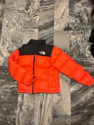 Orange jacka från The North Face - Säljer en orangejacka från The North Face i storlek XS. Används några gånger, OBS en deffekt på bakre armen!