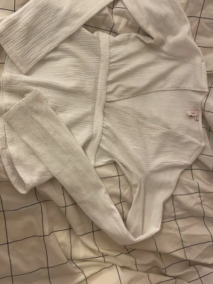 Vit långärmad blus från Nelly - Säljer en vit långärmad blus från Nelly i storlek XXS. Blusen har en markerad midja med ett matchande tygbälte och är gjord i ett strukturerat, stretchigt material. Perfekt för dig som gillar stilrena och enkla plagg med en modern twist. Är lite lortig men går säkert att tvätta bort med hjälp av fläckborttagning 
