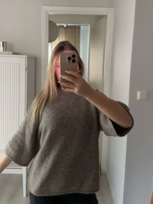 Beige oversized stickad tröja - Mysig beige stickad tröja med avslappnad passform och trekvartsärmar. Tröjan har en enkel design utan synliga mönster eller detaljer och är perfekt för lager-på-lager-stil. Materialet ser ut att vara mjukt och skönt, troligen ull eller ullblandning.