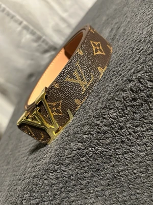 Brunt bälte med guldlogga - Snyggt brunt bälte med elegant guldlogga som ger en lyxig och trendig känsla. Detta är inte ett original, utan ett högkvalitativt alternativ med stilren design och fina detaljer. Perfekt för dig som vill lyfta din outfit och få en exklusiv look utan att betala premiumpris. Passar lika bra till jeans som till mer uppklädda outfits. Ett modernt och stilfullt bälte som verkligen gör skillnad.Pris ej hugget i sten . Längd 105 cm.