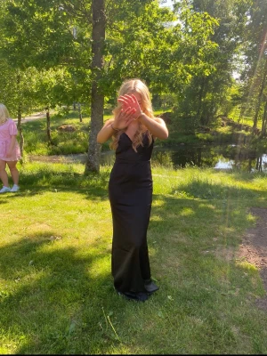 Svart långklänning med v-ringning - Säljer en elegant svart långklänning med v-ringad urringning och smala axelband. Perfekt för festligare tillfällen.