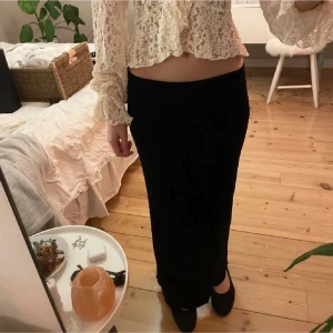 Svart långkjol i sammet - Säljer en svart långkjol i mjuk sammet. Kjolen har en rak och elegant siluett som sitter snyggt i midjan och faller hela vägen ner till anklarna. Perfekt att styla med en spetsblus eller en enkel topp för en chic look.