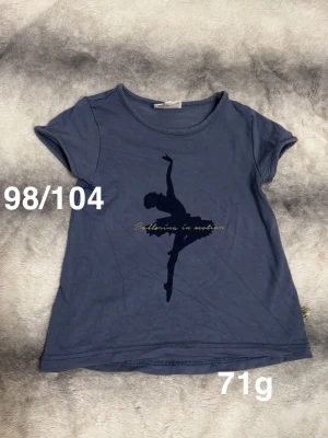 Blå t-shirt med ballerina-tryck - Snygg blå t-shirt med korta ärmar och tryck av en dansande ballerina samt texten 'Ballerina in motion' på bröstet. perfekt för dig som gillar dans och vill ha en chill stil.🌸 Fint använt skick. Storlek 98/104