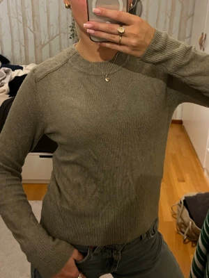 Olivgrön stickad tröja - En enkel och stilren olivgrön stickad tröja med rund halsringning och ribbade muddar. Tröjan har lång ärm och en normal passform, perfekt att slänga på sig till jeans eller kjol. Super mjuk! Använd max en gång!💞