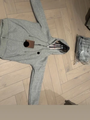 Grå rutig tröja - Skriv så här i beskrivningen, En fräsch och fin Grå tröja med rutig material vid innersidan av luvan, Perfekt nu när det är kallt och kyligt den håller än varm. Den är i storlek S