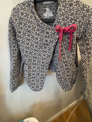 Mönstrad kofta Odd Molly med rosett - Säljer en äkta svartvit mönstrad kofta från Odd Molly med lång ärm och öppen front. Koftan har en snygg rosa rosett som detalj och är stickad i mjukt material. Perfekt för lager på lager och har fickor på sidorna. Inte använt så många gånger så är i väldigt bra skick.☺️☺️☺️kostar runt 300 kr men säljer den för endast 100!!!