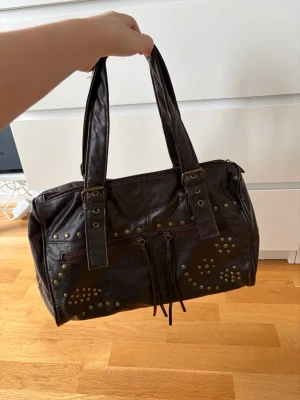 Brun väska - Skitsnygg brun väska men som tyvärr aldrig kommer till användning. Köpt second hand men står Åhléns innuti väskan. Allt på väskan ser nytt och bra ut. Aldrig använd. Mycket utrymme. Guldiga detaljer. Skriv om du har frågor!