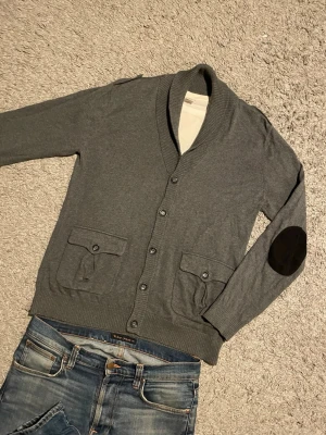 Mörkgrå Cardigan - Säljer en trendig stilren svart cardigan, med fickor! 🙌🏻Perfekt nu för kommande kalla dagar! ❄️Plagget är i nyskick 8,5/10. Tröjan har en klassisk knapp öppning upp till, med en stil som siktar på ”oldmoney” och ”vintage”, men passar till det mesta!🤩Tveka inte på att höra av er!💪🏼